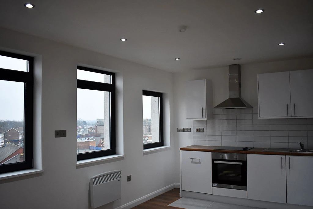 Another view of the kitchen area of an apartment with windows showing the views of the city.